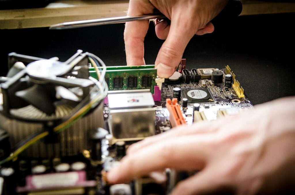 Human hands touching an open motherboard putting RAM in